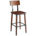 A Lancaster Table & Seating antique walnut wooden bar height table with wooden chairs with metal frames.