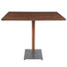 A Lancaster Table & Seating bar height table with a wooden top and metal base.