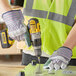 A man using a Cordova double palm work glove to drill holes in a metal surface.