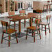 A Lancaster Table & Seating rustic walnut wood table with chairs in a room.