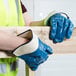 A person wearing Cordova Brawler smooth blue nitrile gloves holding a piece of wood.