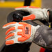 A person wearing Cordova Outlaw Impact leather gloves with orange and black TPR protectors.