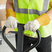 A man wearing Cordova leather warehouse gloves and a safety vest holding a metal frame.