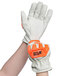 A person wearing Cordova Outlaw Impact leather gloves with orange and white trim.