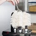 A hand using a white cloth to polish a glass stem with a black and white Campus Products Glass Polisher.