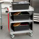 A Lakeside stainless steel utility cart with black containers on it.