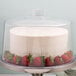 A Tablecraft clear plastic cake cover over a cake with strawberries on top.