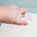 A hand holding a clear plastic Tablecraft cake cover over a cake.