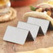 A stainless steel Choice mini taco holder with tacos on a table.