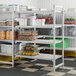 A white Cambro Camshelving® Premium add on unit with four vented shelves holding food.