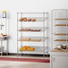 A bakery display with a Regency angled wire shelving rack holding trays of pastries.