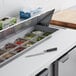 A Beverage-Air sandwich prep table on a counter with food and a knife.