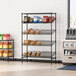 A Regency black metal wire rack with snacks and bread on the shelves.