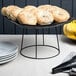 An Acopa black metal display stand with bagels on it.