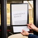 A person holding a Durable black sign holder with the words "conference room iv"