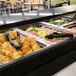 A black Cambro buffet bar base on a hospital cafeteria buffet line with food in containers.