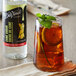 A glass of iced tea with lemon slices and mint leaves on a table.