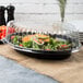 A salad in a black Fineline plastic container with a lid.