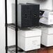 A black wire shelving unit with file folders and boxes on the shelves.