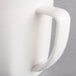 A close up of a Hall China bright white mug with a handle.