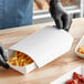 A person in gloves preparing food in a Southern Champion food tray.