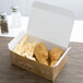 A Take Out lunch box with a fresh print design filled with fried chicken and french fries on a table.