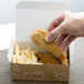 A hand holding a chicken wing and french fries in a Take Out box with a Fresh print design.