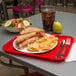 A red Carlisle fast food tray with a sandwich and chips on it.