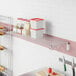 A Regency chrome wire wall mount shelf with clear containers on it.