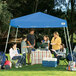 A family sitting under a blue Caravan Canopy tent.