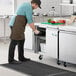 An Avantco worktop freezer on a counter in a professional kitchen being opened by a man in a chef's hat.