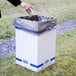 A person's hand putting a bag into a Lavex white corrugated cardboard trash and recycling container.