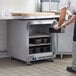 A man in a black apron opening a Beverage-Air undercounter freezer on a counter.