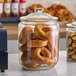 A large clear glass jar with a lid, filled with bagels.