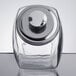 A Choice glass penny candy jar with a chrome lid on a table.