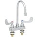 A close-up of a silver T&S deck-mounted workboard faucet with wrist action handles.