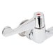 A close-up of a chrome plated Equip by T&S wall mount faucet with white wrist handles.