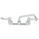 A chrome Equip by T&S wall mount faucet with wrist handles and a swing spout.