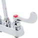 A white T&S deck mounted faucet with red wrist handles.