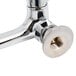 A chrome plated Equip by T&S wall mount faucet with wrist handles and a swing spout.