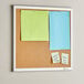 A Quartet cork board with post it notes on it.