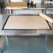 A Sasa Demarle Roul'pat silicone work mat on a stainless steel table with a rolling pin.