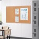 A Quartet cork board with papers on a white wall.