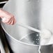 A hand holding a white Carlisle Sparta Spectrum cleaning brush in a pot of liquid.