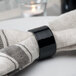 A black Tabletop Classics by Walco napkin ring on a fabric surface.