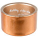 A copper napkin ring with the words, "Tabletop Classics by Walco" in white.
