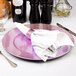 A Tabletop Classics by Walco purple charger plate with silverware on it.