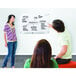 A woman with long hair explaining something on a Quartet white glass markerboard.