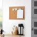 A Quartet cork board with papers on it and a coffee mug on a table.