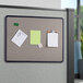 A Quartet gray fabric bulletin board with papers and notes.